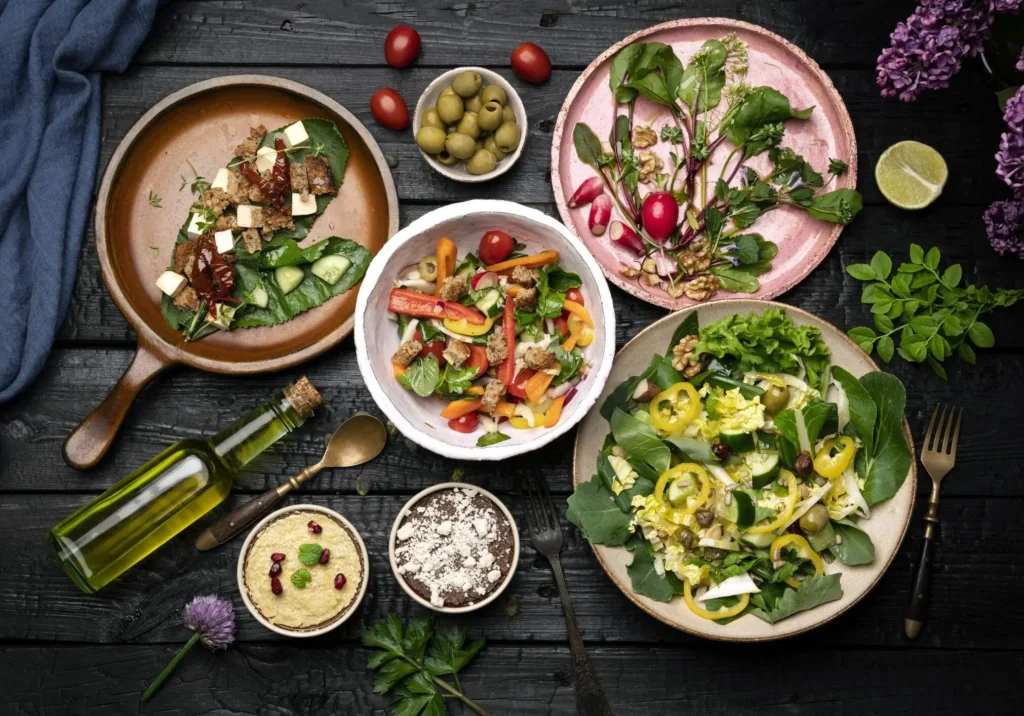 Assorted vegetable salads on dark wooden table.